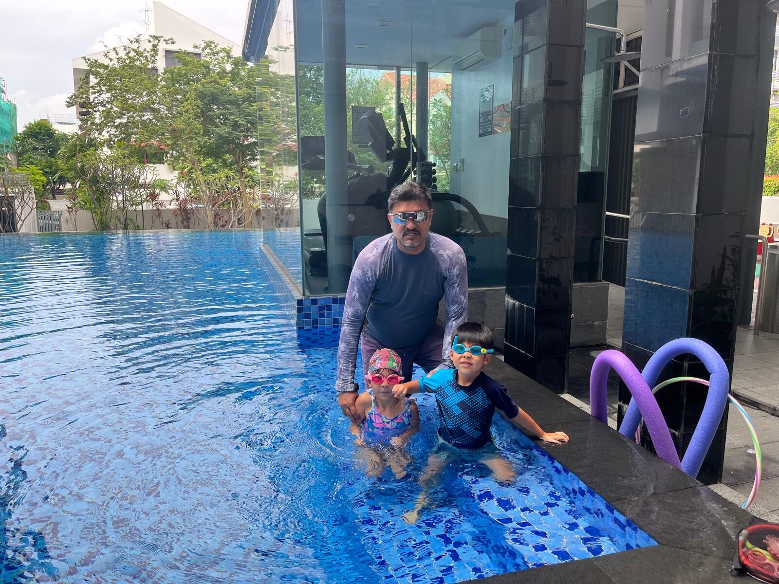 Coach U.K. Singh teaching two young children in a condominium pool in Singapore